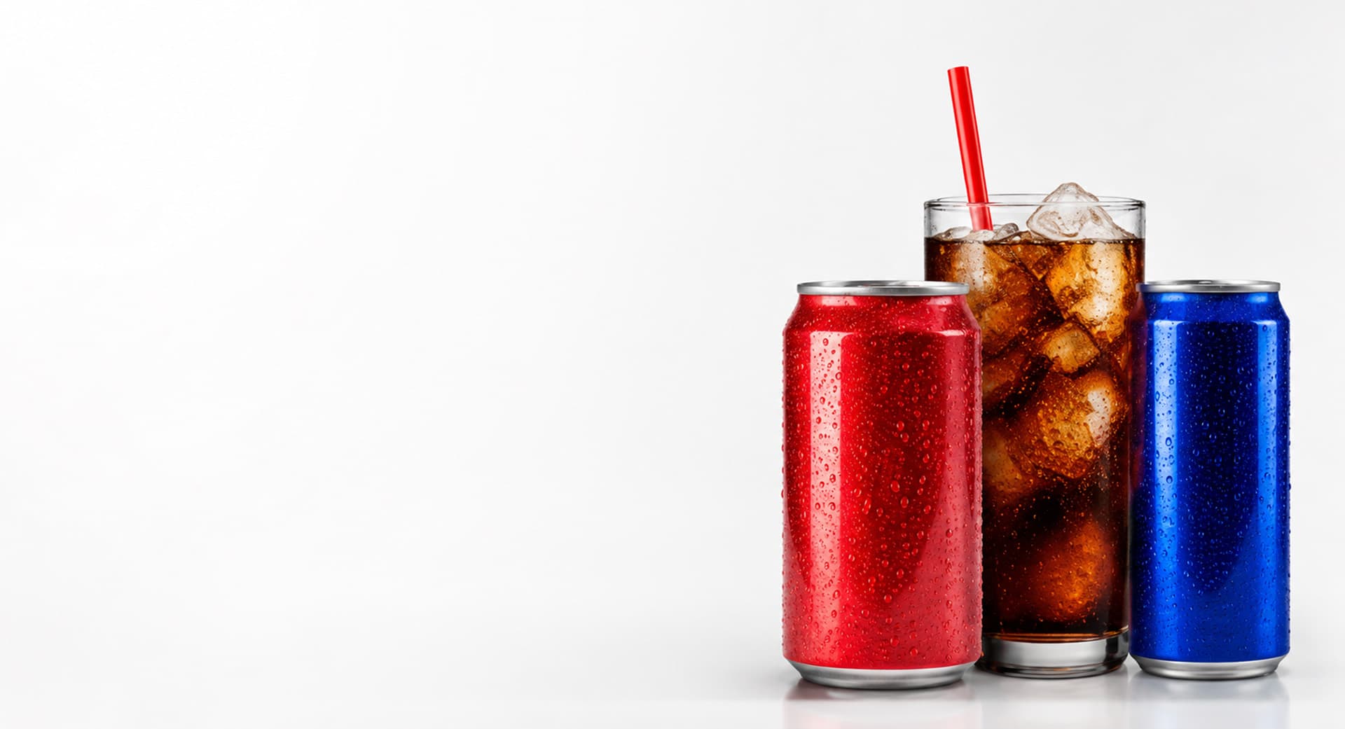 A red soda can, a glass of iced cola, and a blue energy-drink can on a white background
